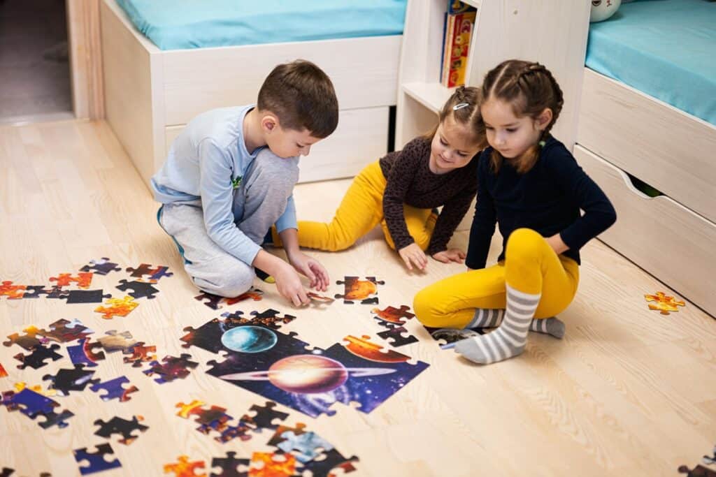 3 enfants font un puzzle ensemble